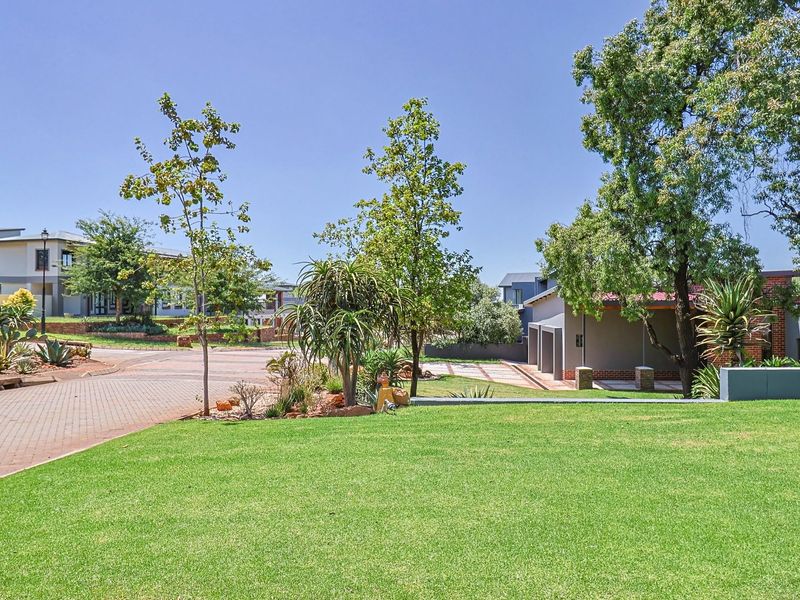 A well-maintained front exterior view featuring a paved driveway, expansive green lawn, and established landscaping within a residential estate setting.