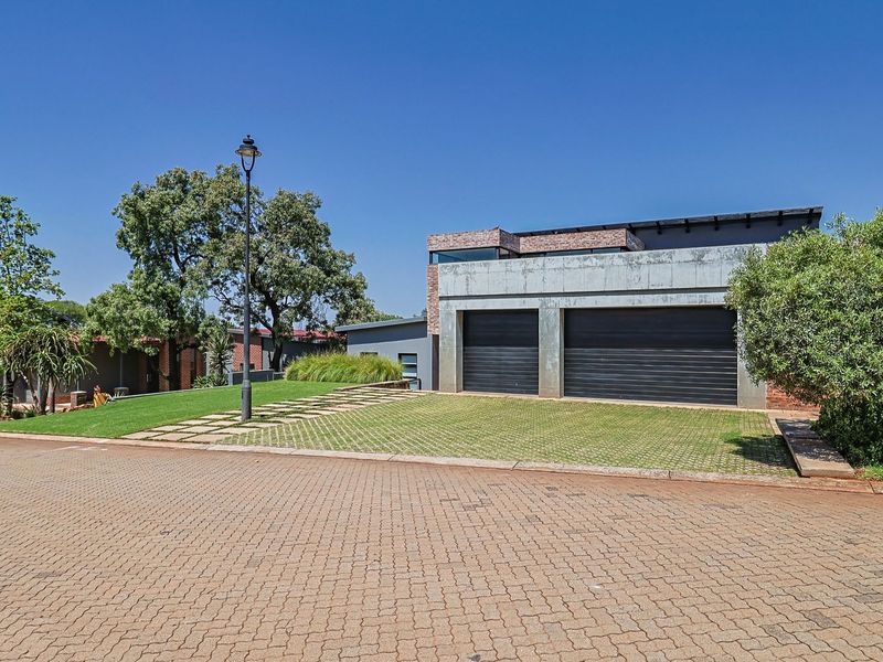 Modern residential property featuring a double garage, clean concrete and brick facade, and a well-maintained front lawn with paved driveway access.