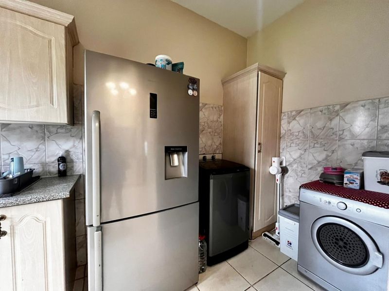 A functional laundry area featuring built-in cabinetry, tiled backsplash, and tiled flooring, providing dedicated space for laundry appliances and storage.