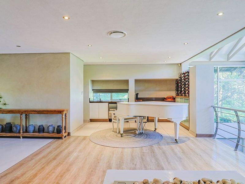 Spacious open-plan living area featuring modern laminate flooring, recessed lighting, built-in wine storage, and large windows providing ample natural light.