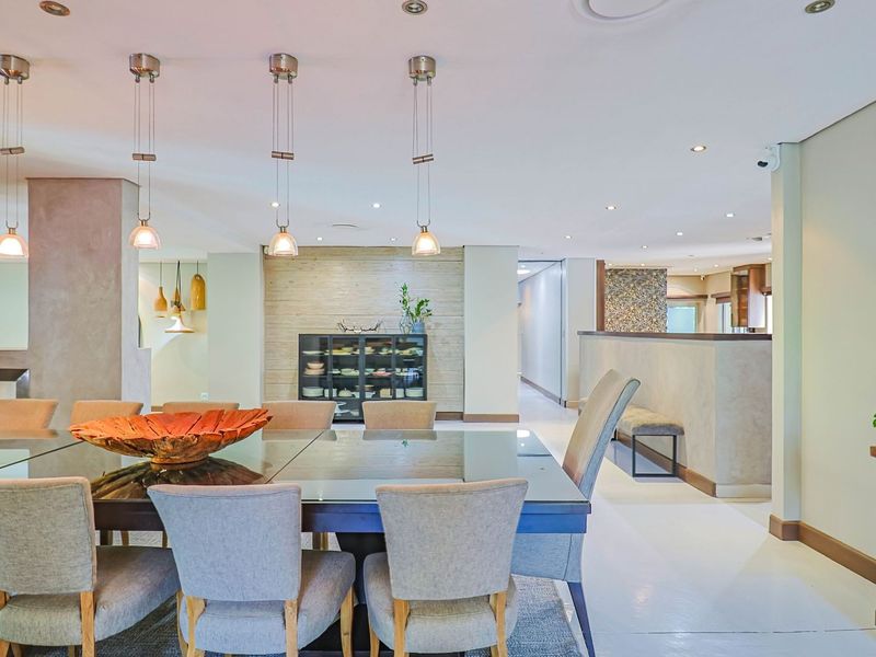 Spacious open-plan dining area featuring modern pendant lighting, recessed downlights, and neutral tiled flooring, creating a bright and inviting atmosphere.