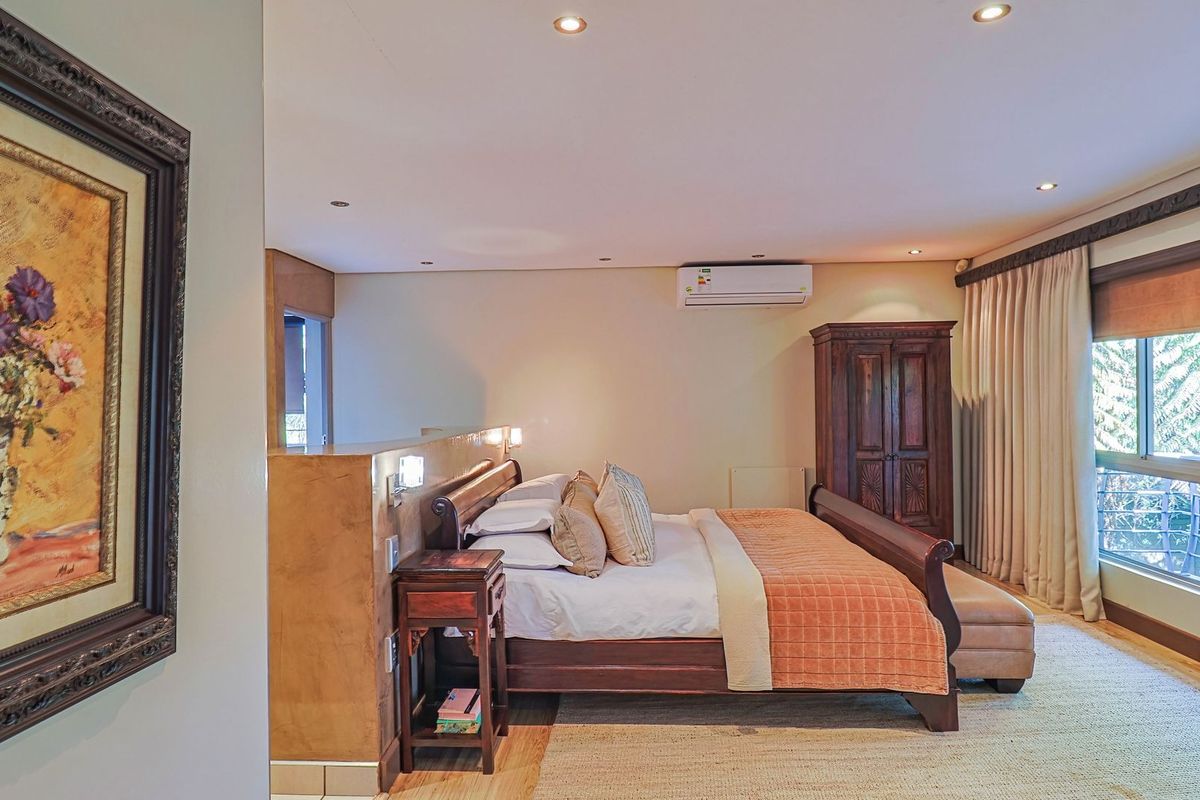 A spacious bedroom featuring a partition wall, recessed lighting, split-system air conditioning, and large windows with integrated curtain tracks.