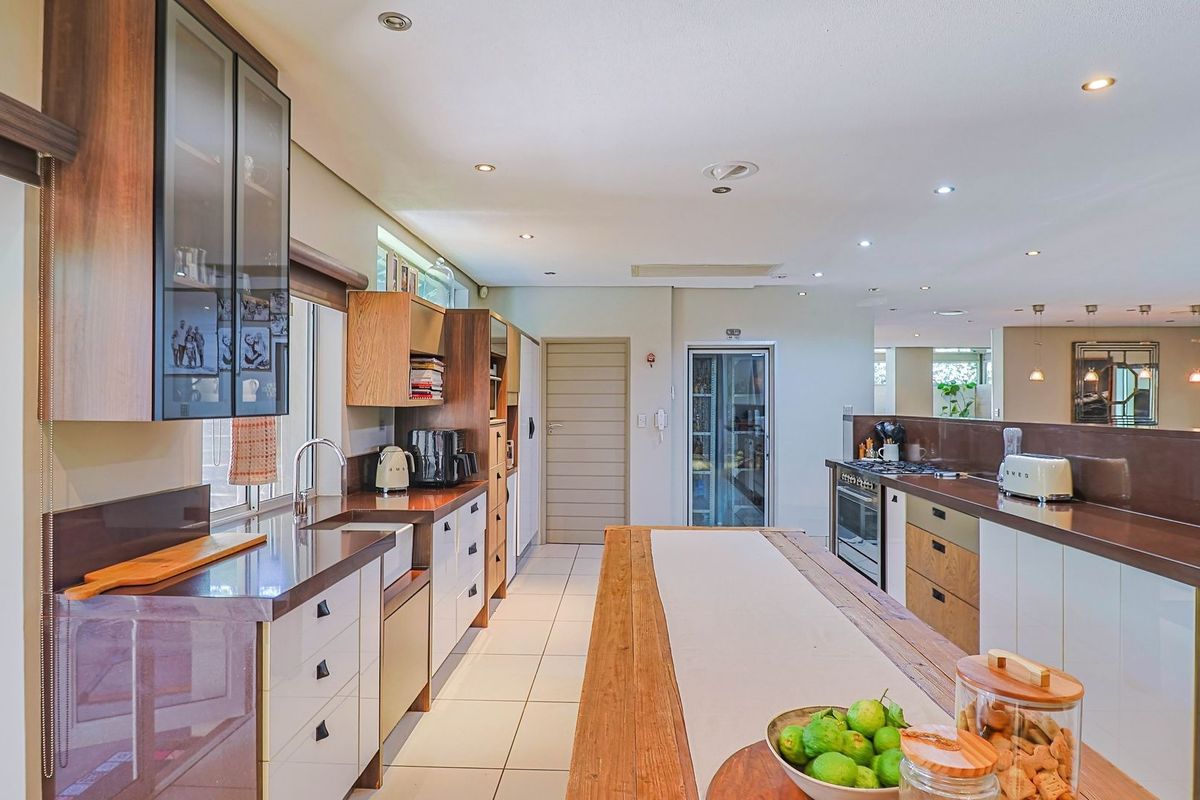 Modern kitchen featuring extensive built-in cabinetry, stone countertops, a central island, and high-quality integrated appliances with recessed lighting throughout.