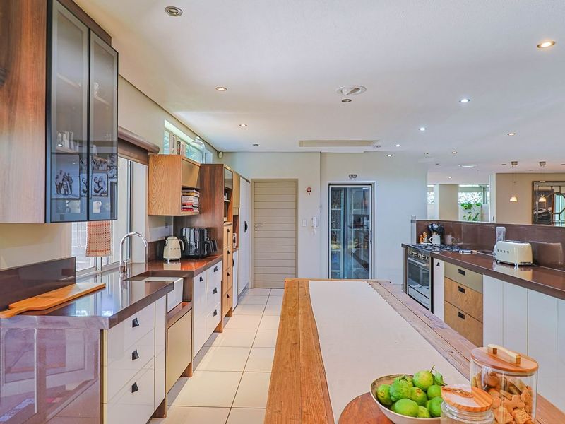 Modern kitchen featuring extensive built-in cabinetry, stone countertops, a central island, and high-quality integrated appliances with recessed lighting throughout.