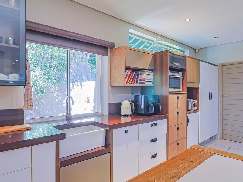 Modern kitchen featuring a farmhouse sink, stone countertops, built-in appliances, and ample cabinetry with a clean, contemporary design.