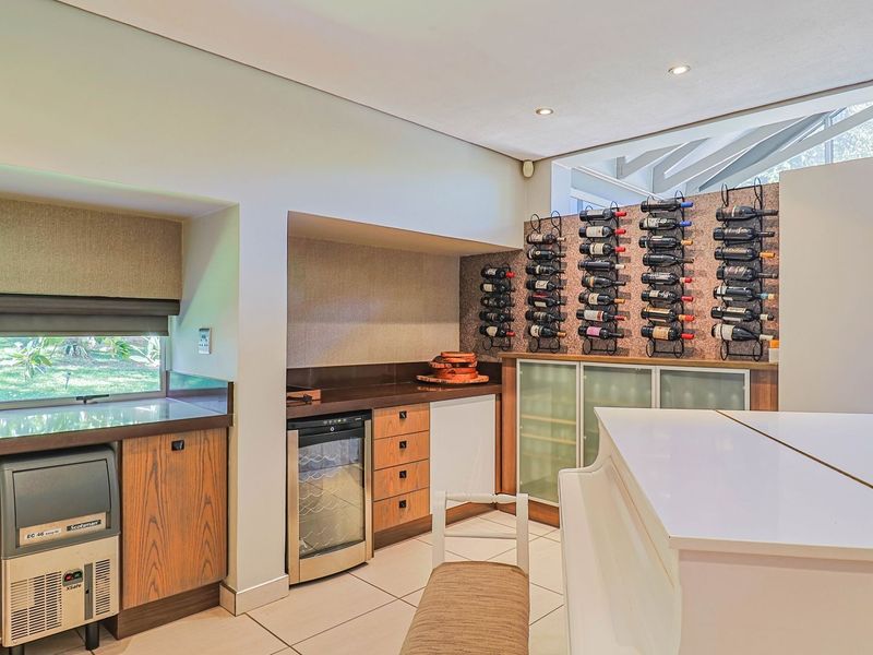 A well-appointed home bar area featuring custom cabinetry, integrated wine storage, an undercounter wine cooler, and a dedicated ice maker.