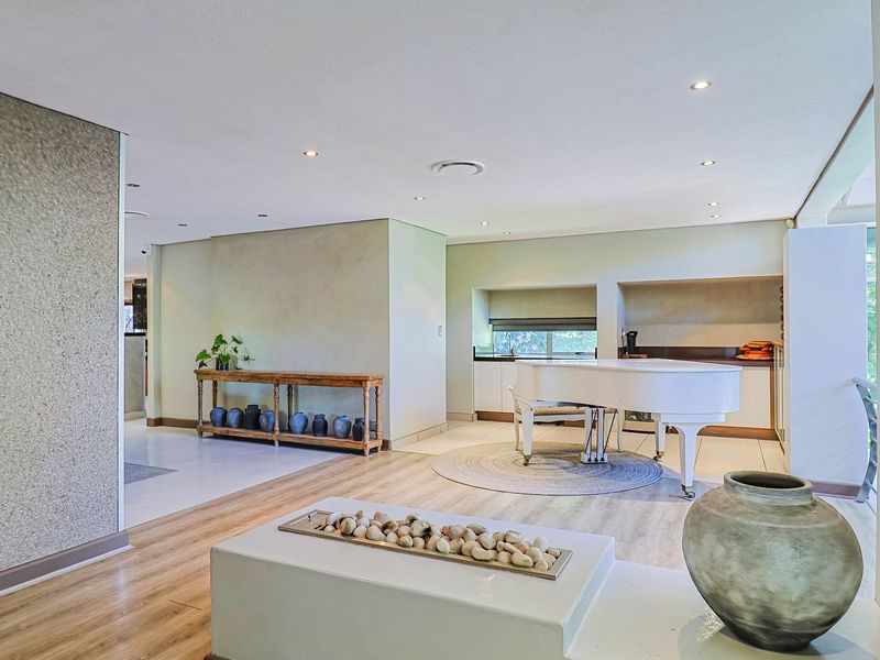 Spacious living area featuring modern recessed lighting, laminate flooring, and a textured feature wall, offering a bright and open atmosphere.