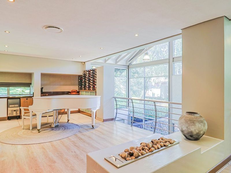 Spacious living area featuring large windows, built-in wine storage, recessed lighting, and a modern fireplace feature with a metal balustrade overlooking the lower level.