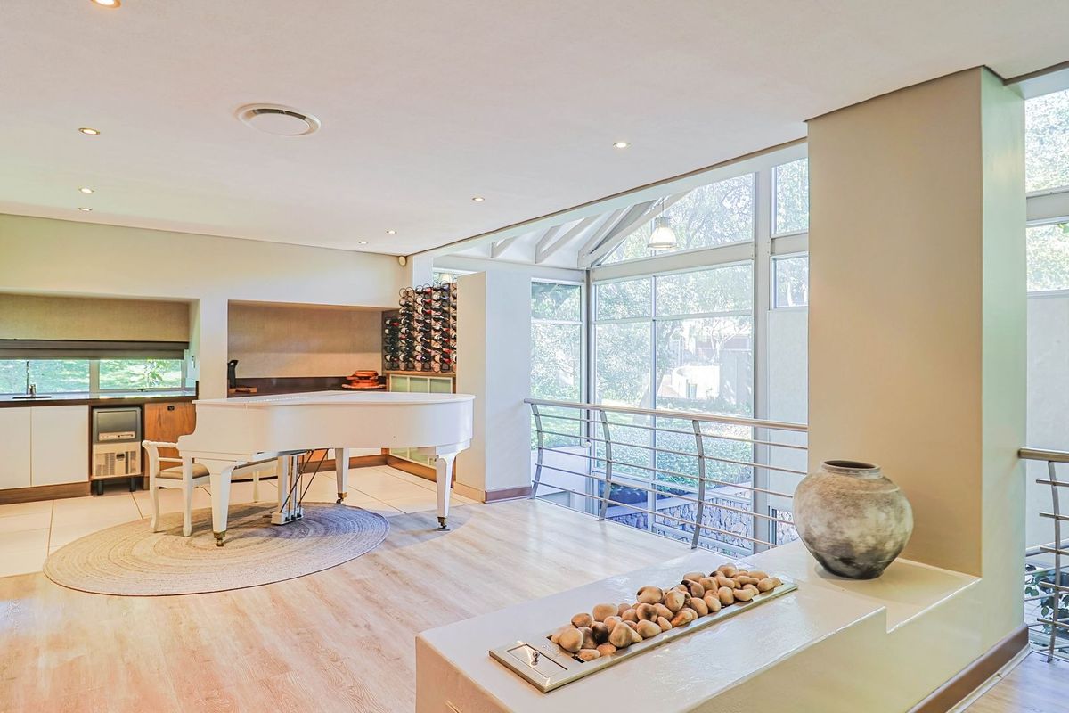 Spacious living area featuring large windows, built-in wine storage, recessed lighting, and a modern fireplace feature with a metal balustrade overlooking the lower level.
