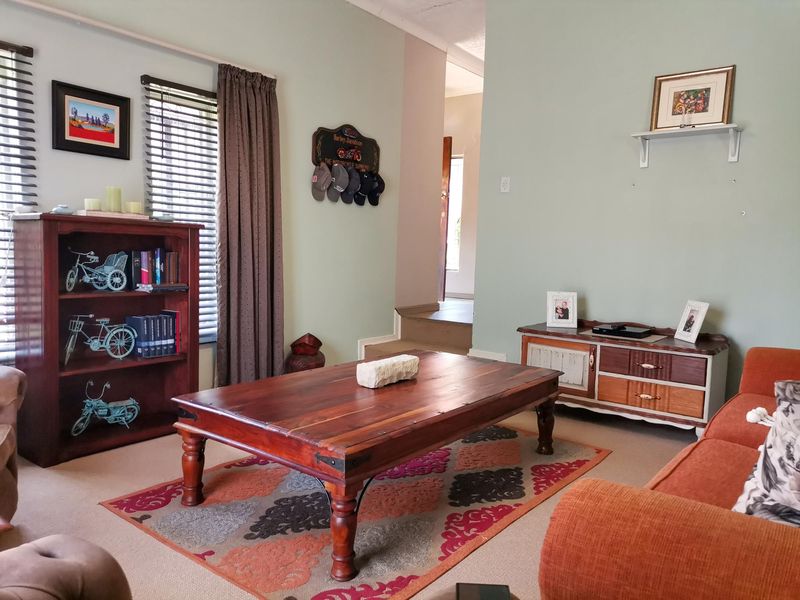 A comfortable living room featuring carpeted flooring and venetian blinds, providing a functional and inviting space for relaxation.