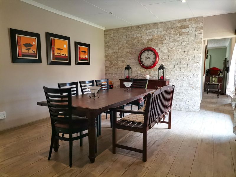 A well-maintained dining room featuring a textured stone accent wall and modern wood-look tile flooring, creating a warm and inviting atmosphere.
