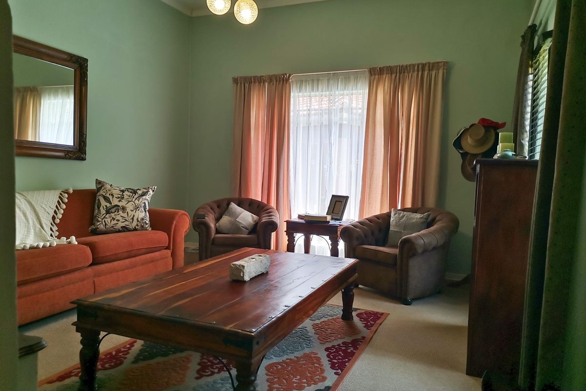 A comfortable living room featuring soft green walls, natural light through window curtains, and a central ceiling light fixture.