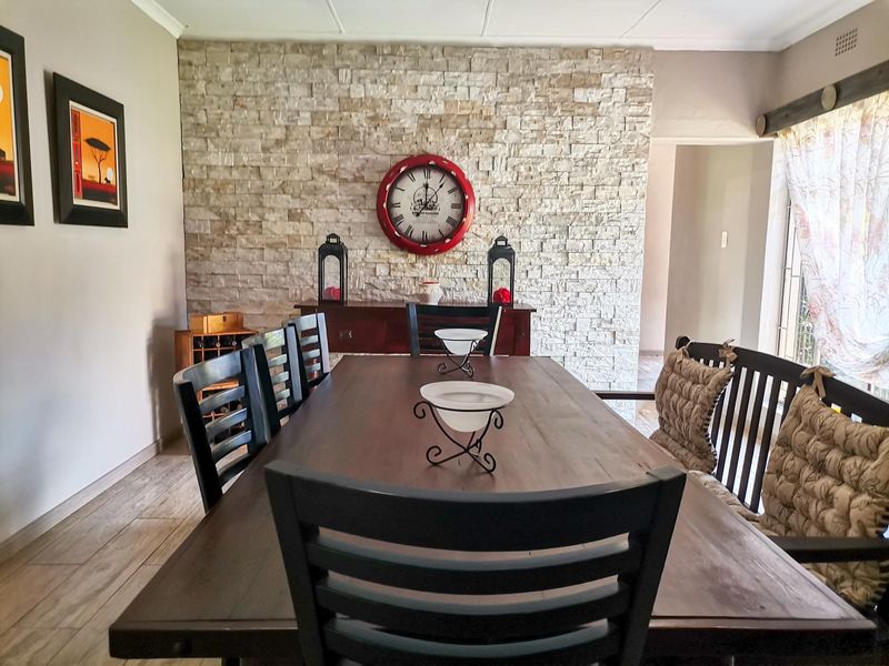 A well-maintained dining room featuring a prominent stone feature wall and tiled flooring, creating a warm and inviting atmosphere for family meals.