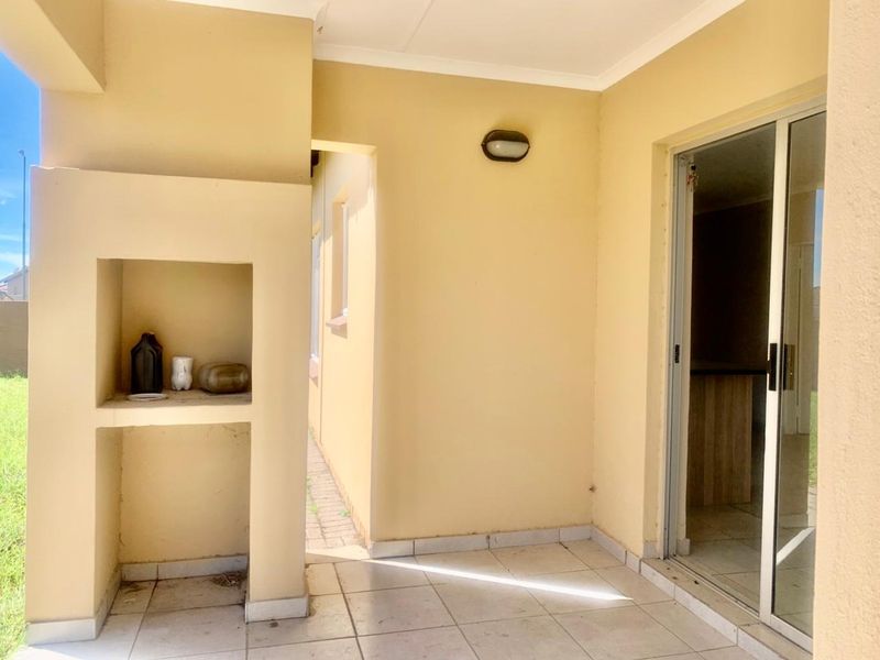 A covered patio area featuring tiled flooring, built-in shelving, and a sliding glass door providing access to the interior living space.