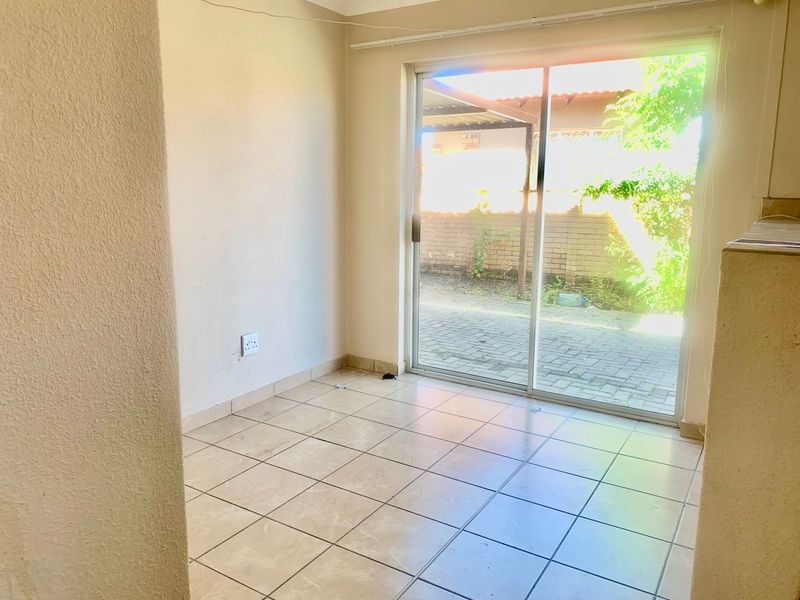 An empty living area featuring tiled flooring and a sliding glass door providing direct access to the rear patio and garden area.