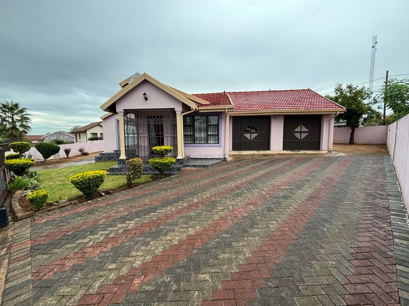 Front view of a residential house featuring a paved driveway, double garage, and a covered entrance with security gate.
