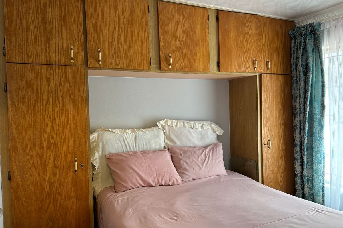 A bedroom featuring extensive built-in wooden cabinetry and overhead storage units surrounding the bed area.