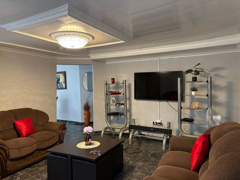 A living room featuring decorative ceiling molding, tiled flooring, and a wall-mounted television setup.