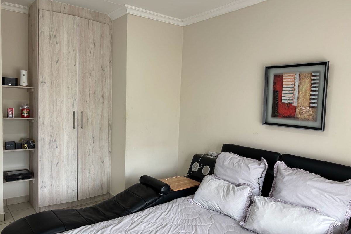 A bedroom featuring a built-in wardrobe with light wood-grain finish, tiled flooring, and decorative coving.