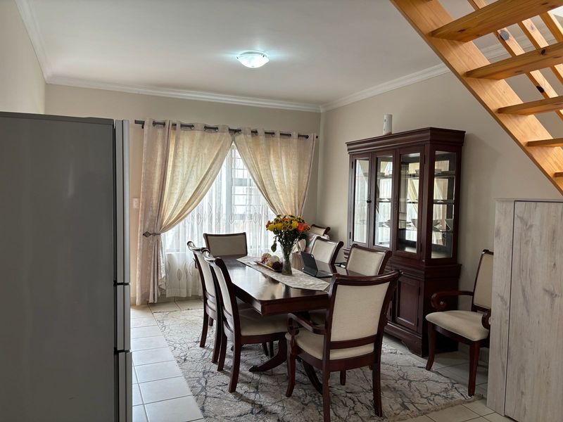 A dining area featuring tiled flooring, ceiling cornicing, and an open wooden staircase leading to the upper level.