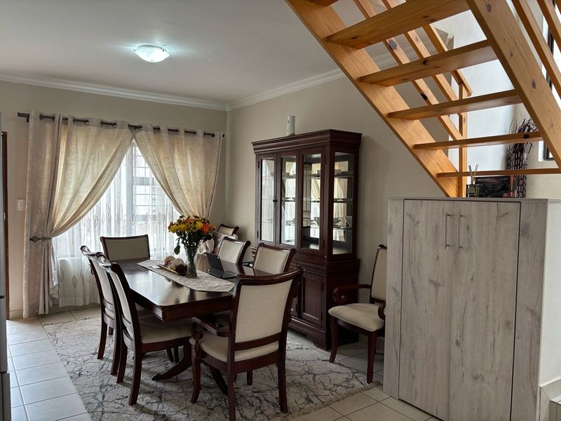 A dining area featuring tiled flooring, coved ceilings, and an open wooden staircase leading to the upper level.