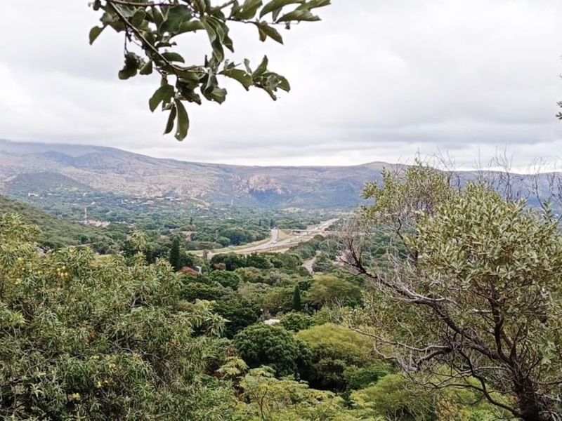 A scenic elevated view overlooking a lush green valley with distant mountains and a road winding through the landscape.