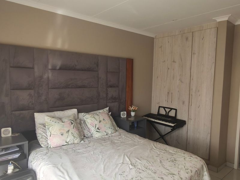 A well-maintained bedroom featuring built-in cupboards, tiled flooring, and direct access to an en-suite bathroom.
