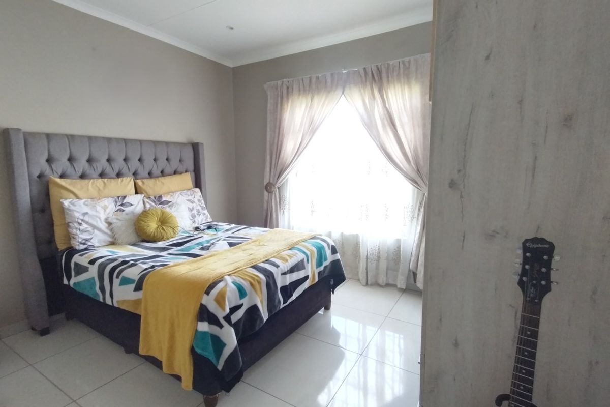 A well-maintained bedroom featuring neutral wall tones, polished tile flooring, and a built-in wardrobe, offering a clean and functional living space.