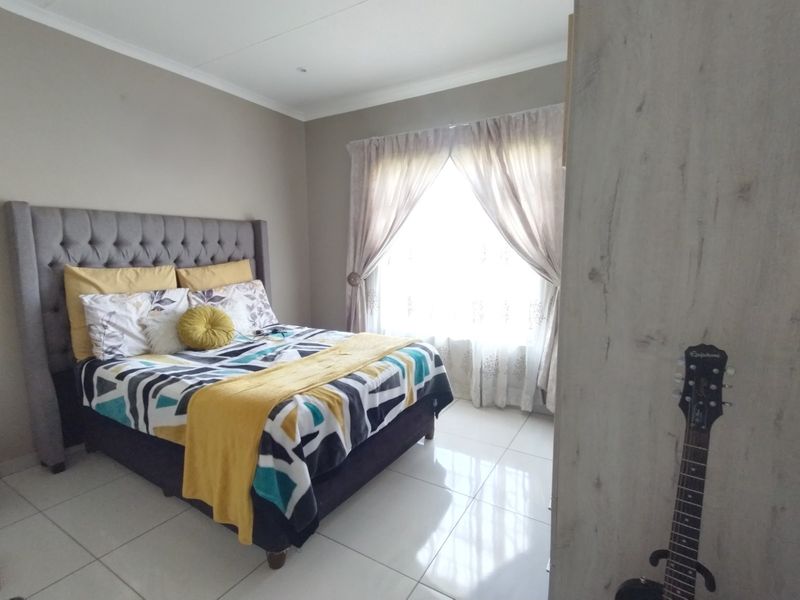 A well-maintained bedroom featuring neutral wall tones, polished tile flooring, and a built-in wardrobe, offering a clean and functional living space.
