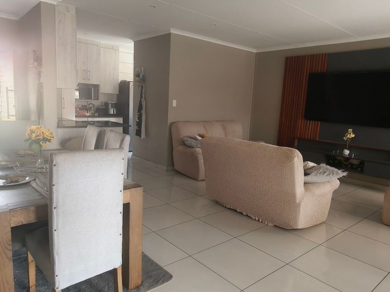 Spacious open-plan living and dining area featuring modern tiled floors, recessed lighting, and a custom built-in media wall unit.