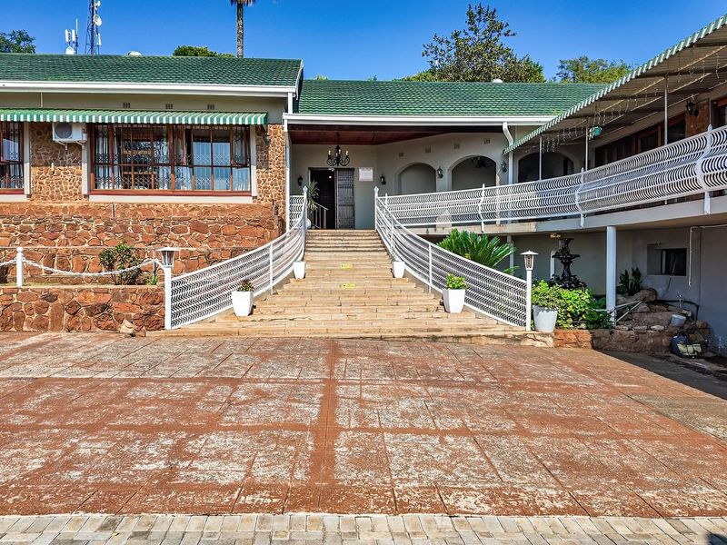 Front elevation of a farm-style property featuring stone cladding, a tiled roof, and a grand central staircase leading to the main entrance.