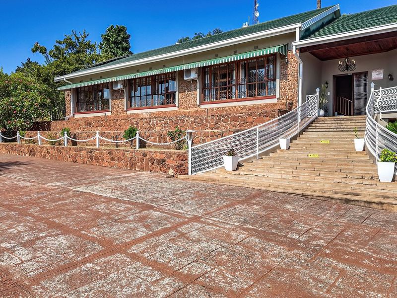 Front elevation of a farm-style property featuring stone masonry, a wide concrete staircase with decorative railings, and a paved entrance area.