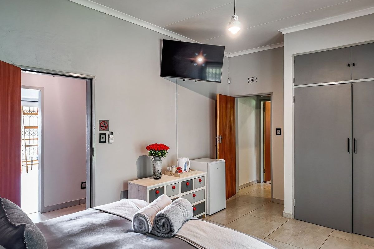 A well-maintained bedroom featuring built-in cupboards, tiled flooring, and neutral wall finishes, providing a clean and functional living space.