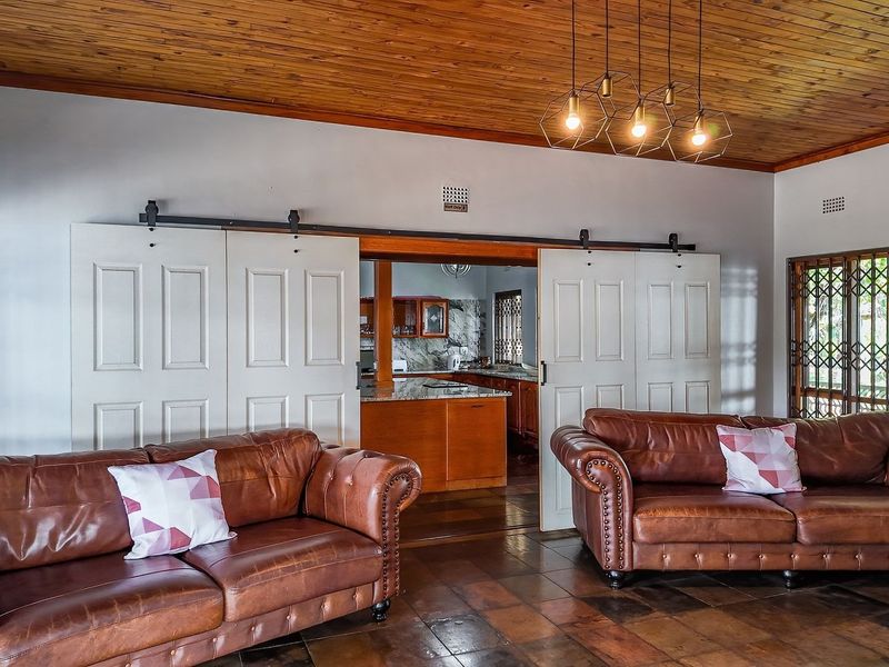 Spacious open-plan living area featuring a warm timber ceiling, tiled floors, and sliding barn doors providing access to the kitchen.