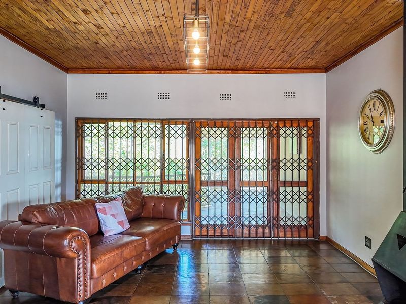 A cozy living room featuring a wood-paneled ceiling, tiled flooring, and a modern freestanding fireplace, with a sliding barn door leading to adjacent space.