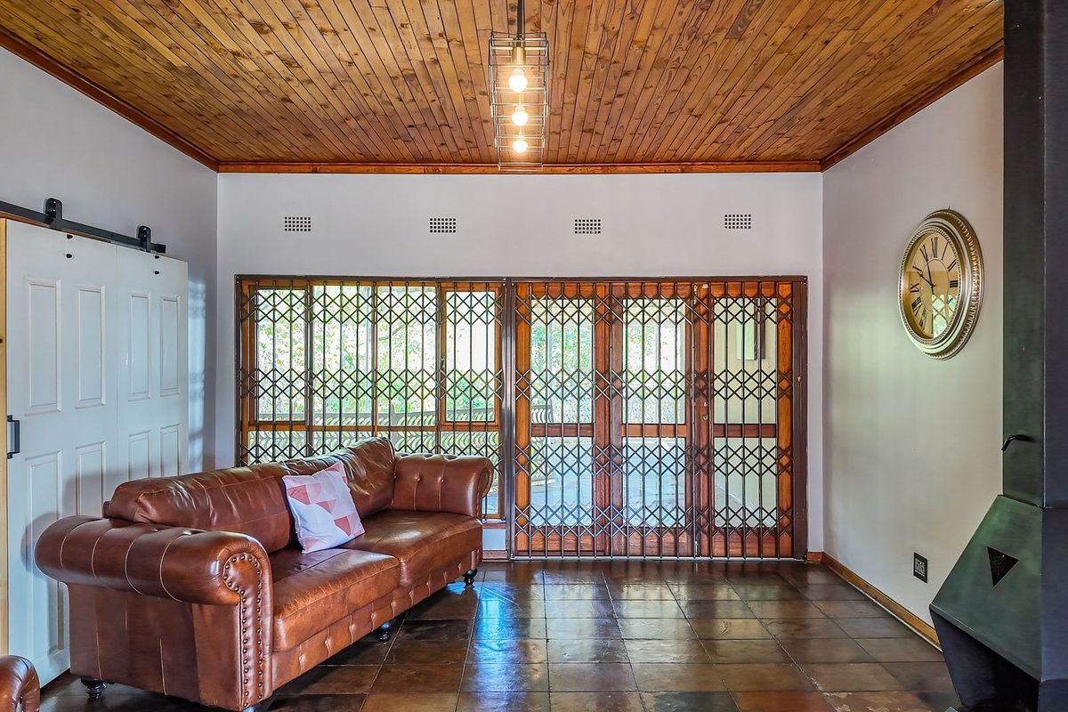 A cozy living room featuring a wood-paneled ceiling, tiled flooring, and a modern freestanding fireplace, with a sliding barn door leading to adjacent space.