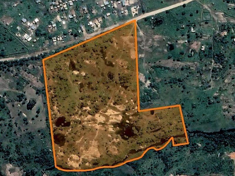 An aerial view of a large, undeveloped residential plot of land with clear boundary lines marked for identification.