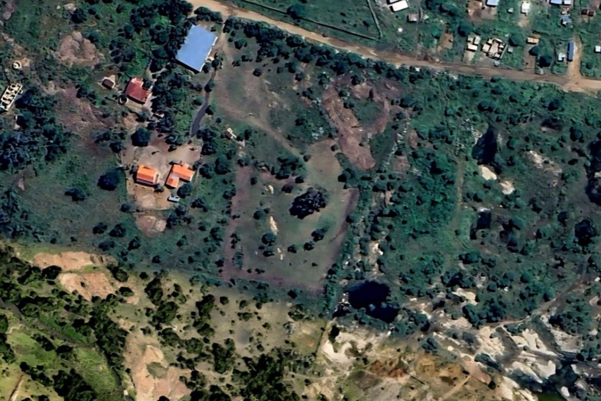 An aerial view of a large, undeveloped residential plot featuring natural vegetation and surrounding rural landscape.