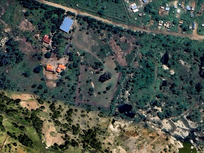 An aerial view of a large, undeveloped residential plot featuring natural vegetation and surrounding rural landscape.