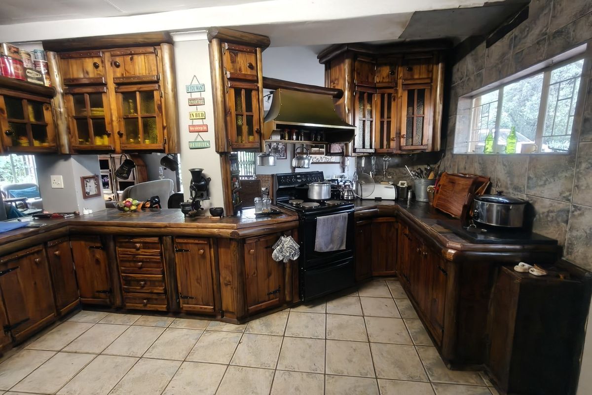 Rustic kitchen featuring extensive wooden cabinetry, tiled backsplash, and a freestanding stove, offering a traditional farm-style aesthetic with functional storage space.