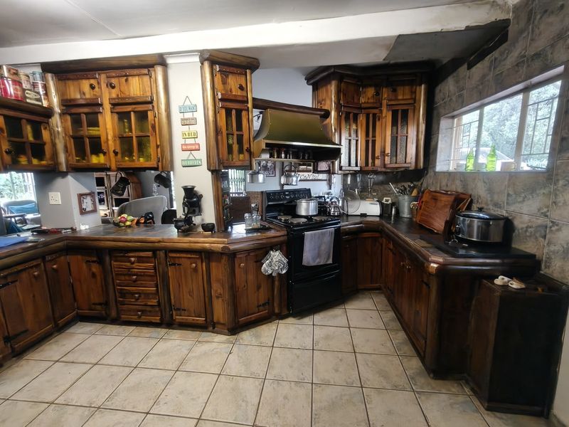 Rustic kitchen featuring extensive wooden cabinetry, tiled backsplash, and a freestanding stove, offering a traditional farm-style aesthetic with functional storage space.