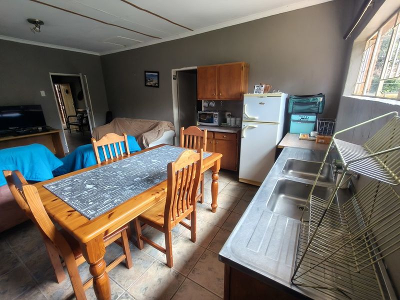 Open plan living and kitchen area featuring tiled floors, built-in wooden cabinetry, and a double stainless steel sink.