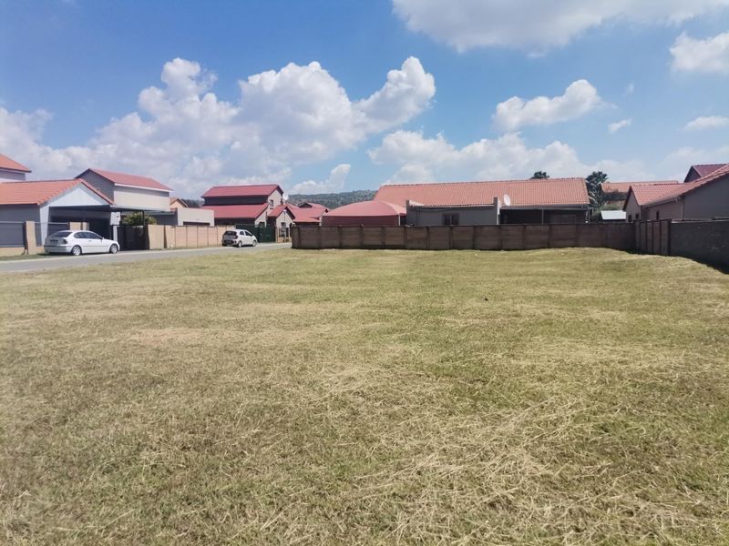 A vacant residential plot of land featuring a level grass surface and established boundary walls in a developed neighborhood.