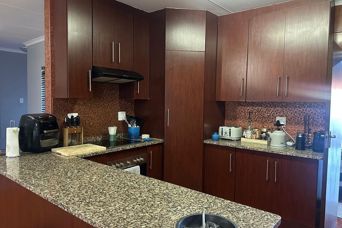 A functional kitchen featuring dark wood cabinetry, granite countertops, and a mosaic tile backsplash, providing ample storage and workspace.
