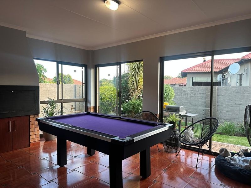 Enclosed patio area featuring tiled flooring, a built-in braai, and large sliding glass doors providing direct access to the garden.