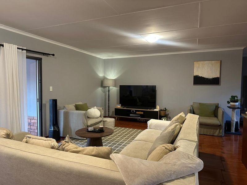 A comfortable living room featuring tiled flooring, neutral wall tones, and a sliding glass door providing access to the outdoor area.