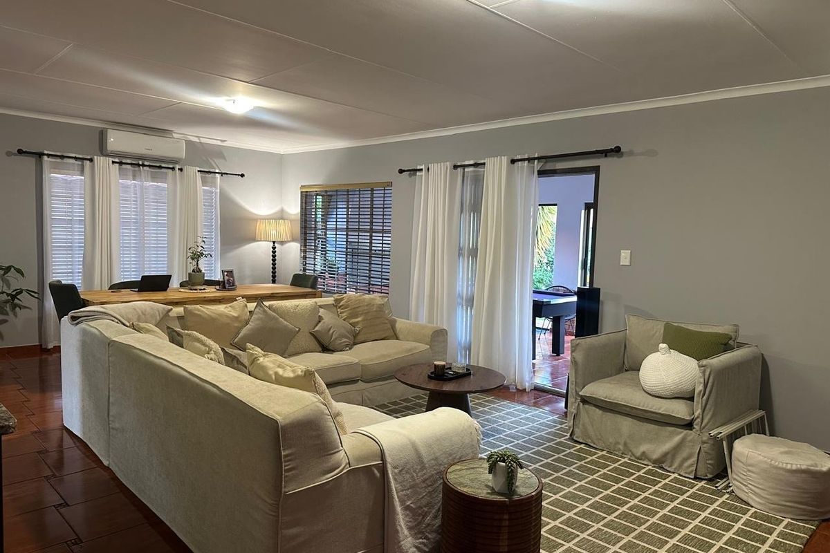 Spacious living room featuring tiled flooring, split-system air conditioning, and direct access to an outdoor patio area through sliding glass doors.