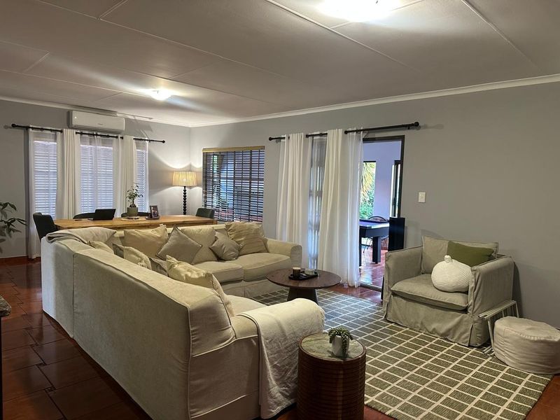 Spacious living room featuring tiled flooring, split-system air conditioning, and direct access to an outdoor patio area through sliding glass doors.