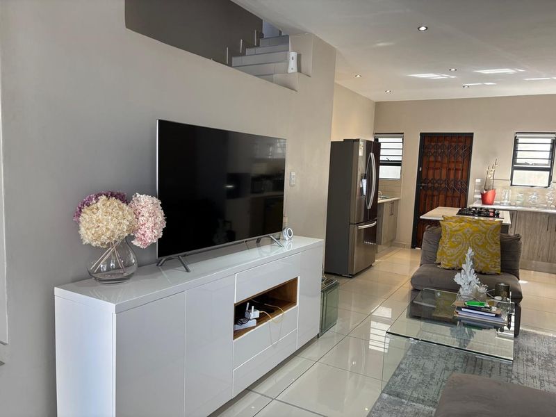 Open-plan living area featuring polished porcelain tiles, recessed lighting, and a seamless flow into the modern kitchen space.