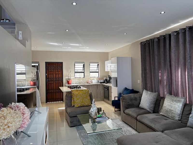 An open-plan living and kitchen area featuring tiled floors, recessed lighting, and a functional kitchen layout with built-in appliances.